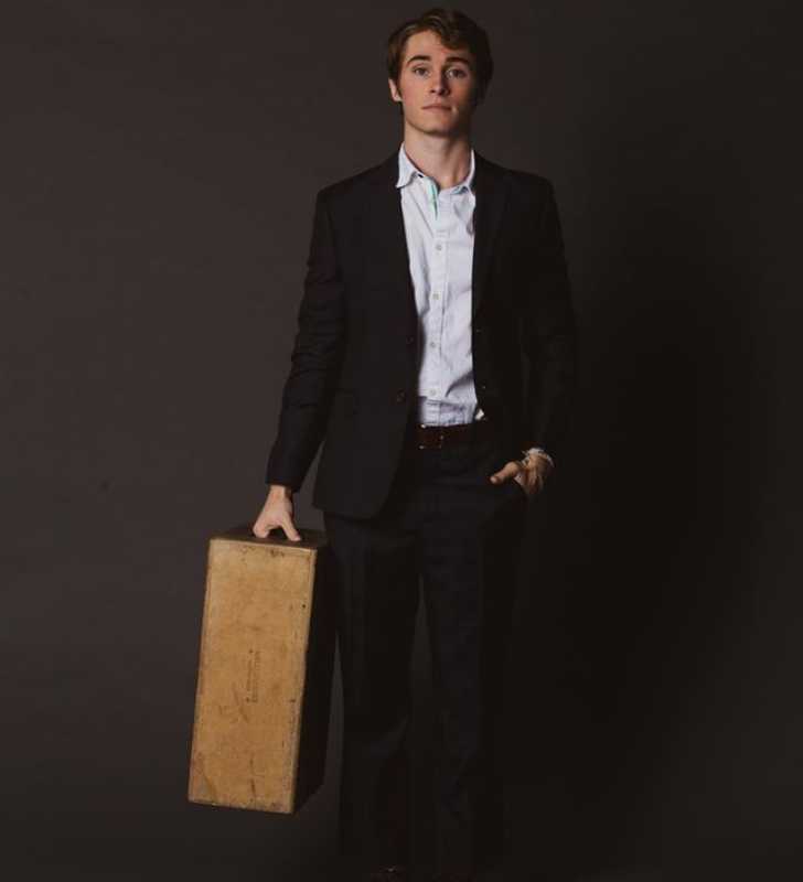 Picture of Michael Provost posing for a photo holding briefcase in right hand and putting his left hand inside pocket with classic black suit and white shirt.